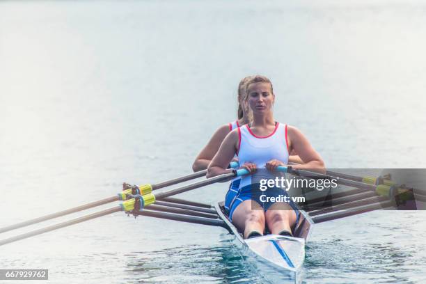 two women rowing on a lake - crew rowing stock pictures, royalty-free photos & images