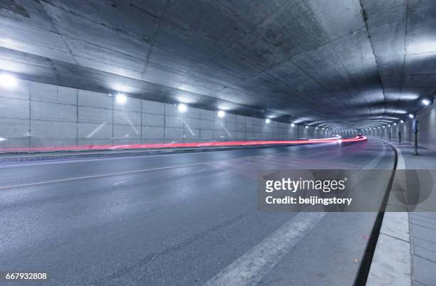 autopista vacía a un túnel del camino iluminado - túnel de carretera fotografías e imágenes de stock