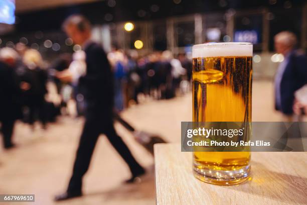 pint of beer and people queue in the background - pint glass stock pictures, royalty-free photos & images