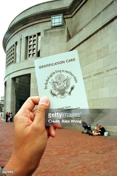 Hand holds a copy of the United States Holocaust Memorial Museum identification card as the Museum is seen in the background July 11, 2000 in...