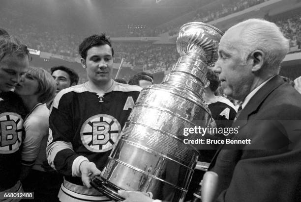 John Bucyk of the Boston Bruins is handed the Stanley Cup Trophy by NHL President Clarence Campbell after the Bruins defeated the St. Louis Blues in...