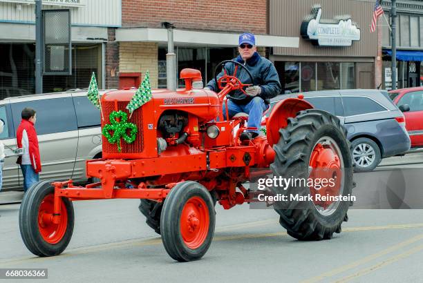 View of an unidentified man as he drives a restored, mid-century Allis-Chalmers 'WD' tractor during the the annual Saint Patrick's Day Parade,...