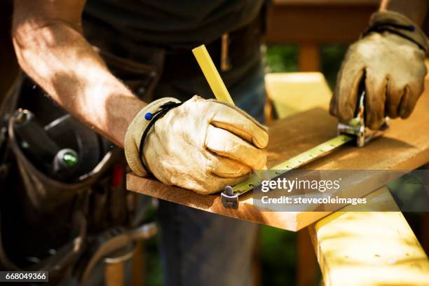 falegname che misura una tavola di legno. - glove foto e immagini stock