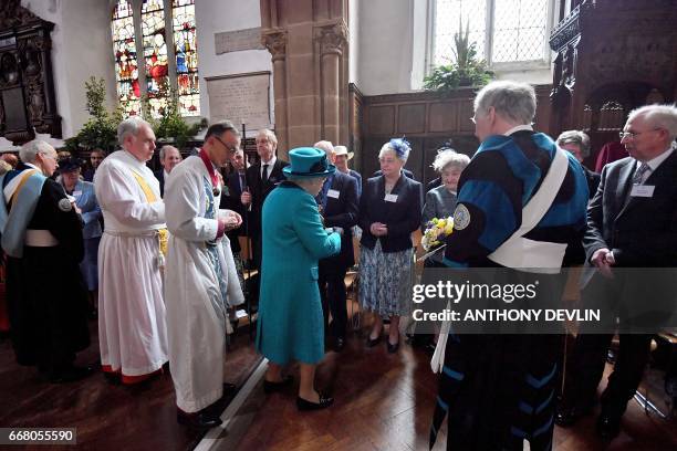 Britain's Queen Elizabeth II hands out Maundy money during the Royal Maundy service at Leicester Cathedral on April 13, 2017 in Leicester.