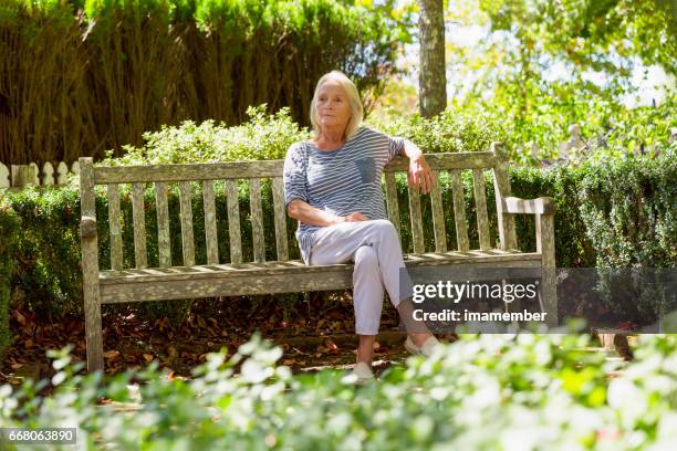 portrait of modern, attractive mature woman sitting in the park - só uma mulher idosa imagens e fotografias de stock