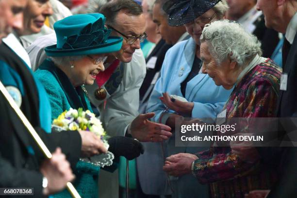 Britain's Queen Elizabeth II hands out Maundy money during the Royal Maundy service at Leicester Cathedral on April 13, 2017 in Leicester.