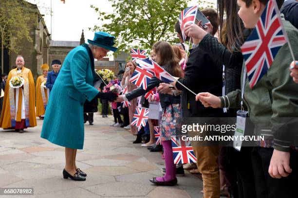 Britain's Queen Elizabeth II is given flowers by Amber Dowman as she meets local children following the Royal Maundy service at Leicester Cathedral...