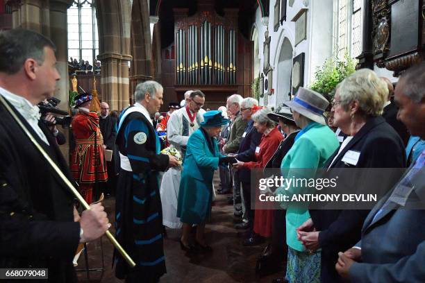 Britain's Queen Elizabeth II hands out Maundy money during the Royal Maundy service at Leicester Cathedral on April 13, 2017 in Leicester.
