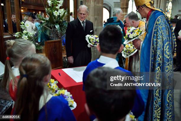 Britain's Prince Philip, Duke of Edinburgh prepares to sign the guest book during the Royal Maundy service at Leicester Cathedral on April 13, 2017...