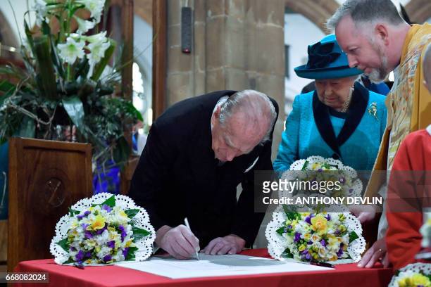 Britain's Prince Philip, Duke of Edinburgh signs the guest book as Queen Elizabeth II looks on during the Royal Maundy service at Leicester Cathedral...