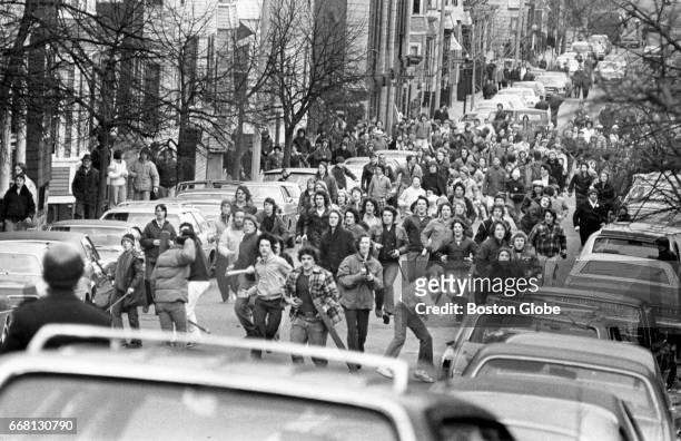 Crowd of antibusing demonstrators storm up East Sixth Street in South Boston armed with rocks and clubs on Feb. 15, 1976. A demonstration erupted...