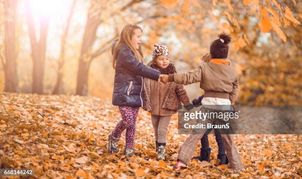 small girls playing ring-around-the-rosy during autumn day in the park. - ring around the rosy stock pictures, royalty-free photos & images