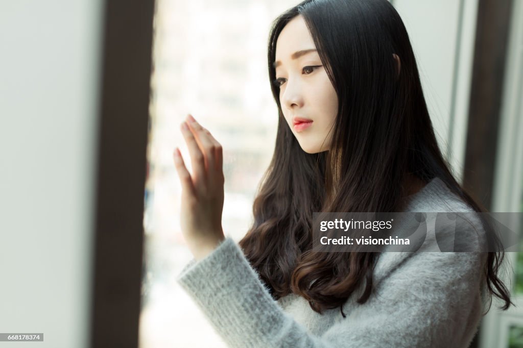 Ritratto di giovane bella ragazza guardando attraverso la finestra
