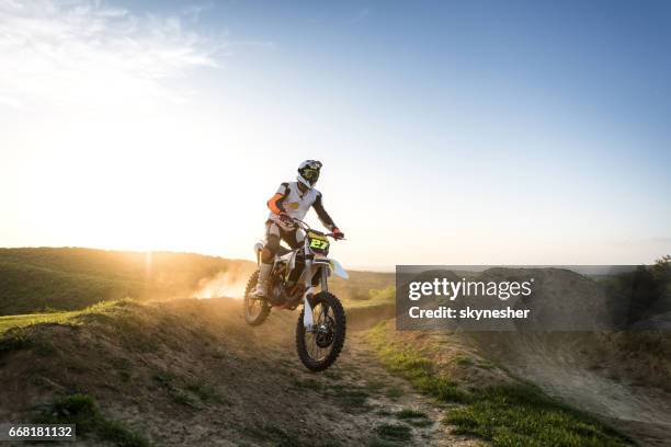 motocross-fahrer rennen über schmutz hügel bei sonnenuntergang. - motocross stock-fotos und bilder