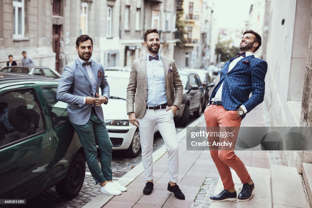 Three young good looking tailors laughing on the street