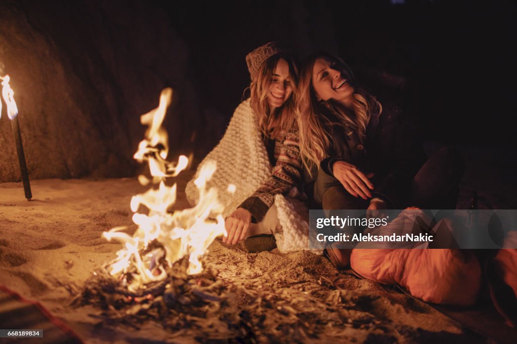 Amigos disfruten de la noche en la playa por el fuego