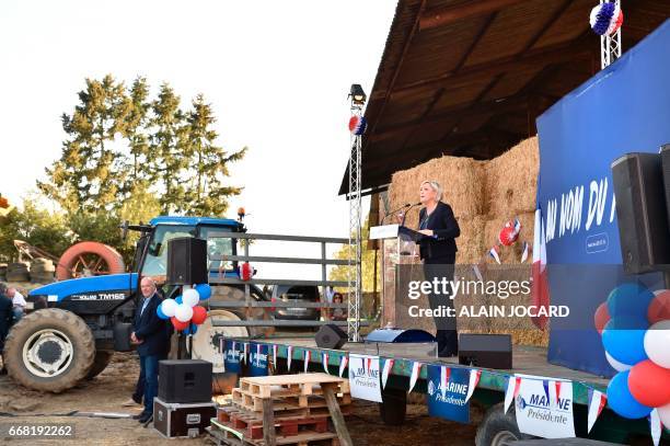 French presidential election candidate for the far-right Front National party Marine Le Pen delivers a speech as her bodyguard Thierry Legier looks...