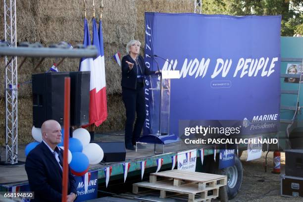 French presidential election candidate for the far-right Front National party Marine Le Pen gestures as she delivers a speech as her bodyguard...