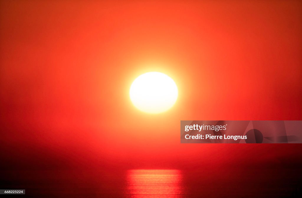 Close-up of a red sunset in a the fog above the Pacific Ocean