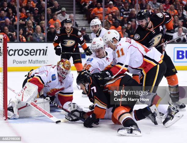 Brian Elliott of the Calgary Flames makes a save as Rickard Rakell of the Anaheim Ducks looks for a rebound with and Mikael Backlund and Michael...