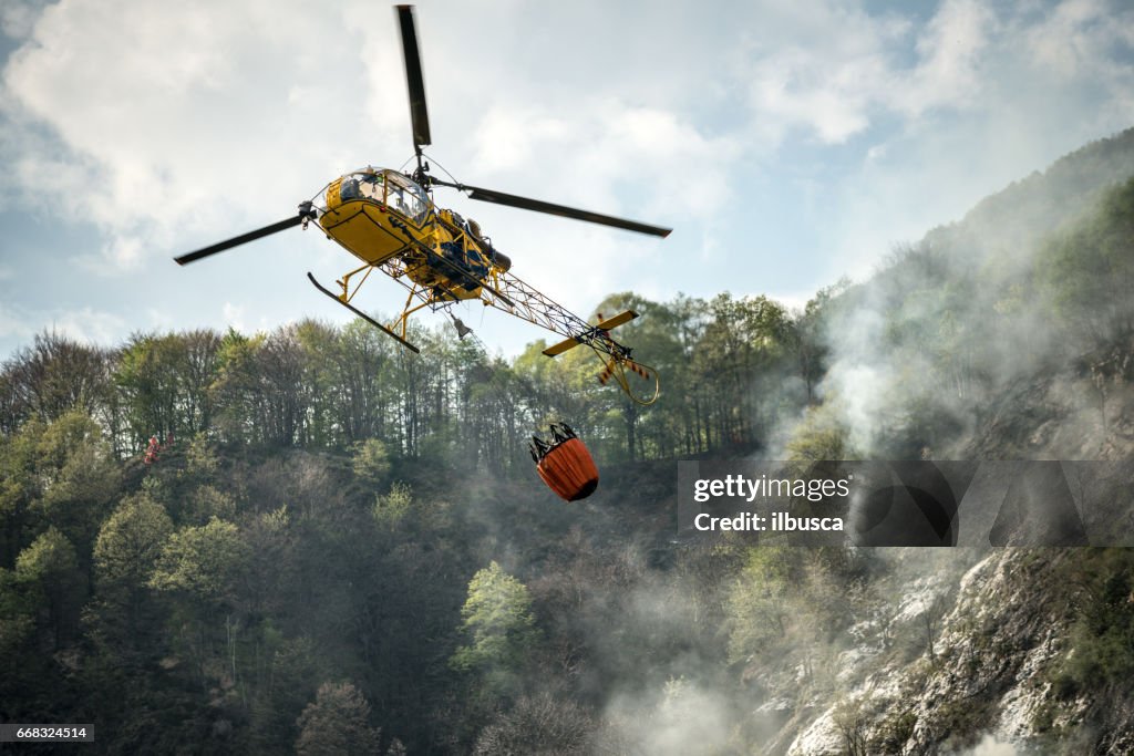 Firefighter helicopter putting out a fire on mountain forest