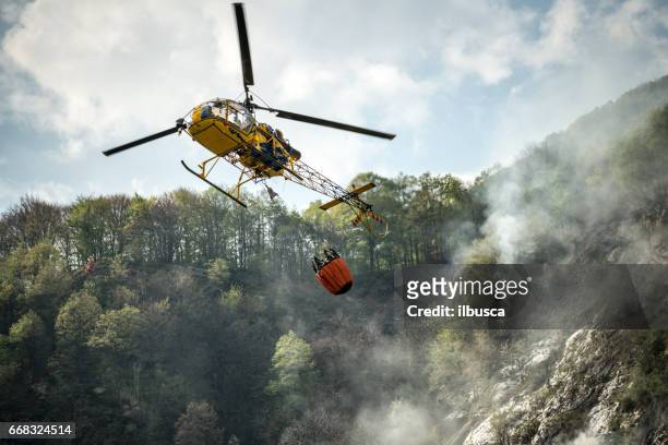 firefighter helicopter putting out a fire on mountain forest - forces of nature stock pictures, royalty-free photos & images