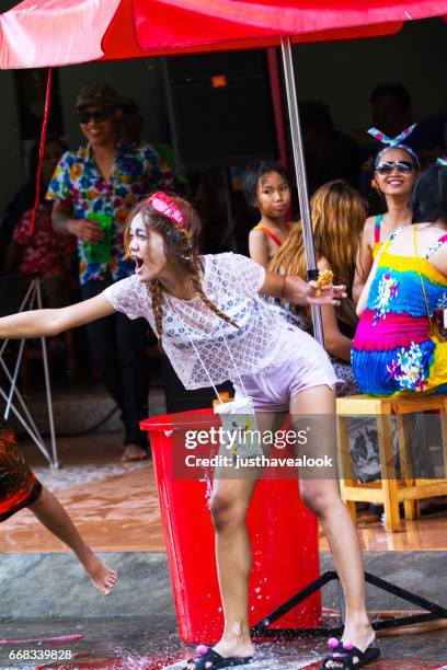 thaise vrouw sproeien van water op songkran - städtische straße stockfoto's en -beelden