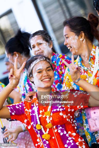 donne tailandesi felici in camicie colorate con fiori a songkran - menschengruppe foto e immagini stock