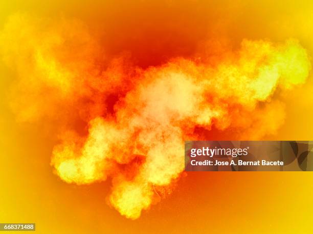 explosion of a cloud of powder of particles of  colors yellow and orange on a orange background - explotar photos et images de collection