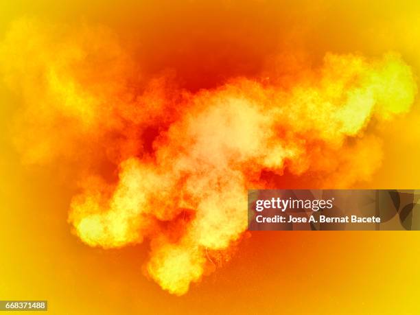 explosion of a cloud of powder of particles of  colors yellow and orange on a orange background - color vibrante stockfoto's en -beelden