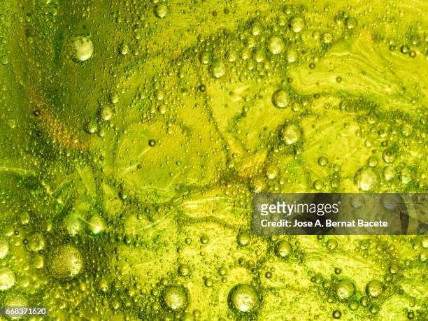 full frame of the textures formed by the bubbles and drops of oil in the shape of circle floating on a gold and green colors background - burbuja stock pictures, royalty-free photos & images