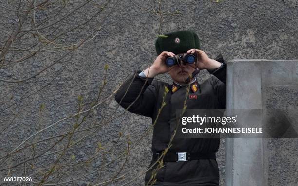 North Korean soldier uses his binoculars to look across the Yalu river near Sinuiju, opposite the Chinese border city of Dandong on April 14, 2017. A...