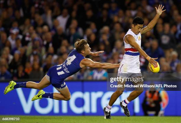 Lin Jong of the Bulldogs is tackled by Shaun Higgins of the Kangaroos during the 2017 AFL round 04 match between the North Melbourne Kangaroos and...