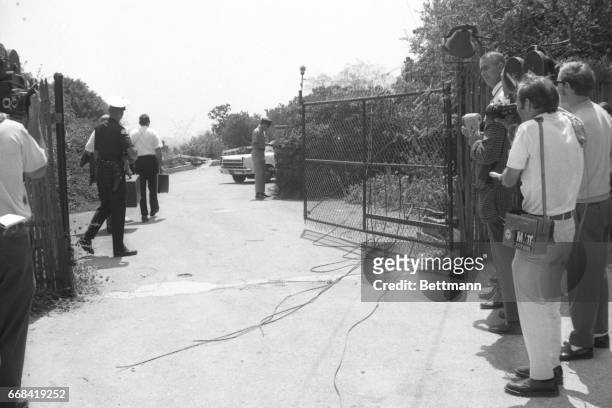 Los Angeles, California: Members of the Los Angeles Police Department crime lab pass by newsmen as they go through the gate that leads to the house...