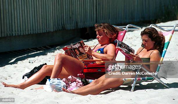 Woman reads a magazine with John F. Kennedy Jr. And wife Caroline Bessette on the cover, , July 15, 2000 on a beach in Hyannis MA. Kennedy Jr. Died...