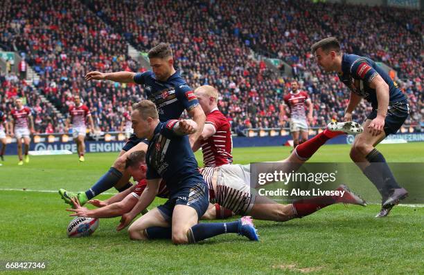 Joe Burgess of Wigan Warriors dives through to score the opening try during the Betfred Super League match between Wigan Warriors and St Helens at DW...