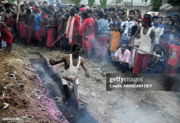 An Indian Hindu devotee runs over smouldering charcoal during the ritual of Shiva Gajan in the village of Pratapgarh on the outskirts of Agartala on...