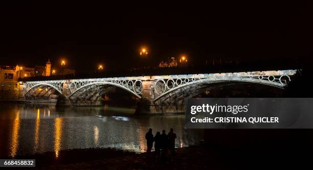 Penitents of 'La Esperanza de Triana' brotherhood cross the Triana bridge during a Holy Week procession on April 14, 2017. Compartir Imagen para...