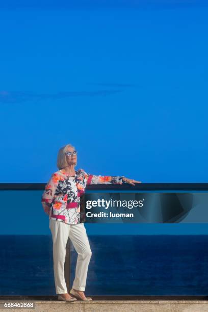 elegante alte dame außerhalb direkt am meer - despreocupado stock-fotos und bilder