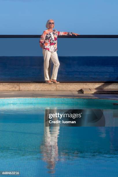 elegante dama de edad cerca de la piscina - mulheres fotografías e imágenes de stock