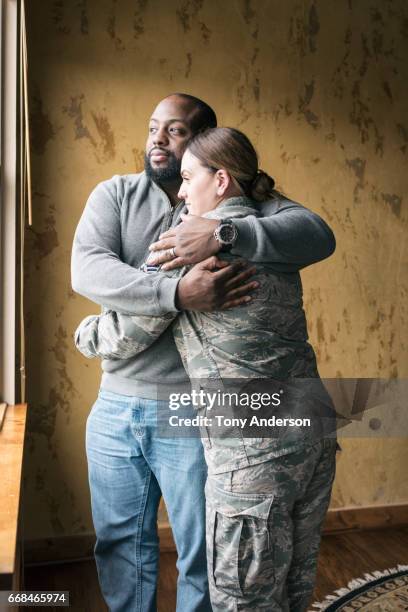 caucasian woman in military uniform embracing her african american husband - couple jeans shirt stock-fotos und bilder