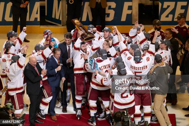 Frozen Four: Denver Will Butcher victorious holding up trophy with teammates on ice after winning game vs Minnesota Duluth at United Center. Chicago,...