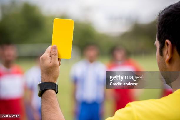 el árbitro muestra una tarjeta amarilla en un partido de fútbol - arbitro futbol fotografías e imágenes de stock