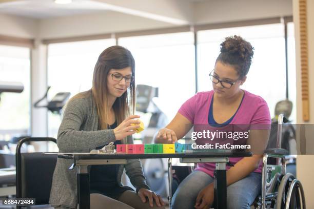 woman works with teenage girl at rehab clinic - terapia ocupacional imagens e fotografias de stock
