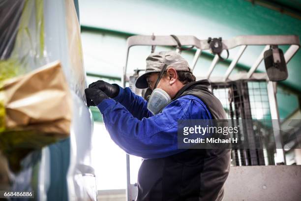 worker wearing mask inspecting van body in car factory - tarpaulin stock-fotos und bilder