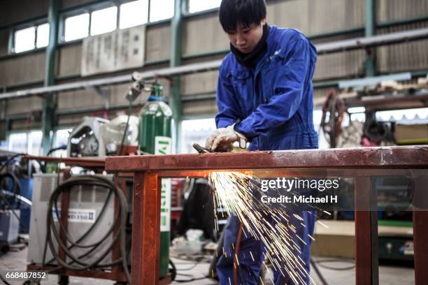 young worker cutting steel items at factory - man cutting wire stockfoto's en -beelden