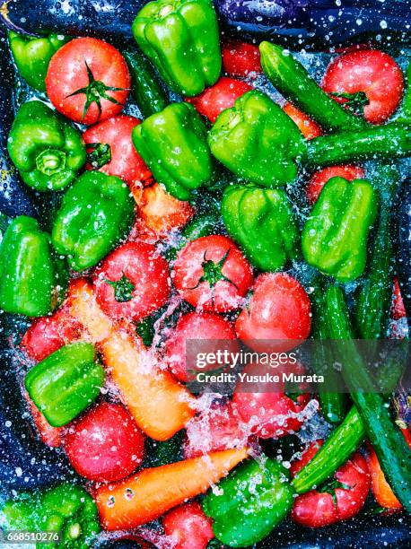 over view of water falling on vegetable - pepper spray stockfoto's en -beelden