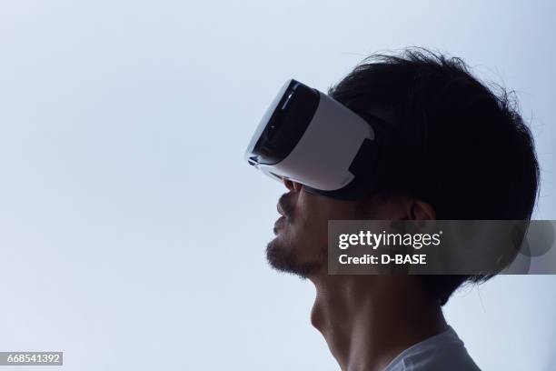 man using a virtual reality headset - realidade virtual imagens e fotografias de stock