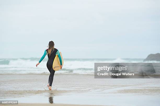 surfer running toward sea with surf board. - wetsuit stock pictures, royalty-free photos & images