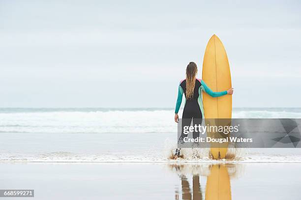 surfer standing with board looking out to sea. - wet hair back stock pictures, royalty-free photos & images